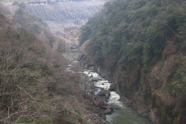 Engebeli bir vadi boyunca, engebeli arazi ve yemyeşil bitki örtüsüyle çevrili.