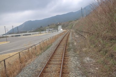 Topraklar, yemyeşil alanlar ve bulutlu gökyüzünün altındaki dağlar..
