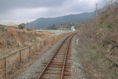 Topraklar, yemyeşil alanlar ve bulutlu gökyüzünün altındaki dağlar..