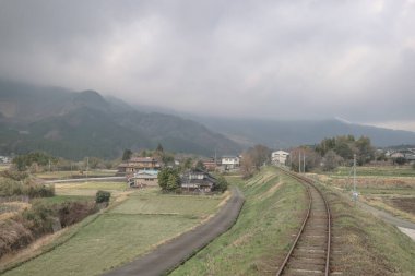 Çevresi yemyeşil demiryolu ile çevrili kırsal istasyon.