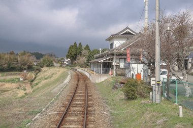 Geleneksel bir evin yanında kırsal tren raylarının kıvrımlı olduğu sakin bir manzara
