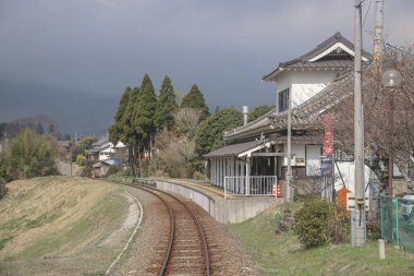 Geleneksel bir evin yanında kırsal tren raylarının kıvrımlı olduğu sakin bir manzara
