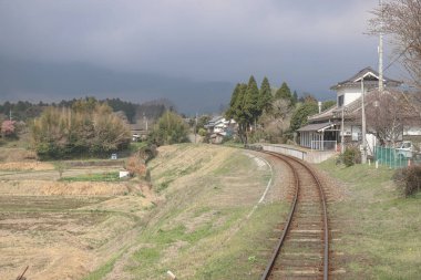 Geleneksel bir evin yanında kırsal tren raylarının kıvrımlı olduğu sakin bir manzara