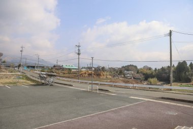 Çevresindeki yeşil alanlar ve elektrik direkleri olan sakin bir kırsal yol.