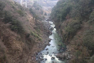 Engebeli bir vadi boyunca, engebeli arazi ve yemyeşil bitki örtüsüyle çevrili.