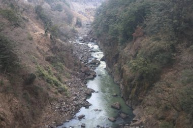 Engebeli bir vadi boyunca, engebeli arazi ve yemyeşil bitki örtüsüyle çevrili.