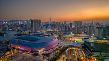 Mimari bina gün batımında aydınlandı, bir hareketlilik ile çevrili.