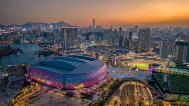 Mimari bina gün batımında aydınlandı, bir hareketlilik ile çevrili.