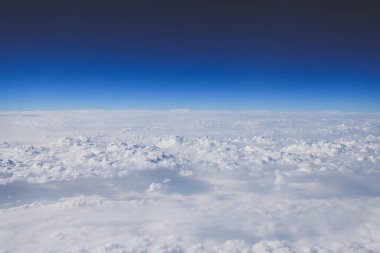 Ufuk boyunca uzanan bulutlar canlı mavi bir gökyüzünün altında,