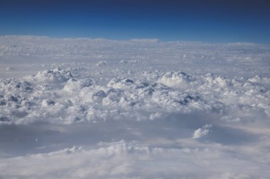 Ufuk boyunca uzanan bulutlar canlı mavi bir gökyüzünün altında,