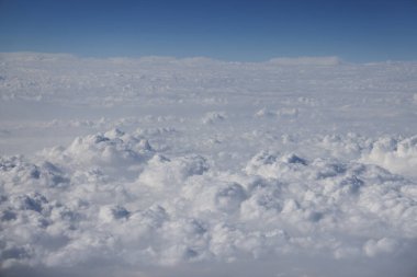 Ufuk boyunca uzanan bulutlar canlı mavi bir gökyüzünün altında,