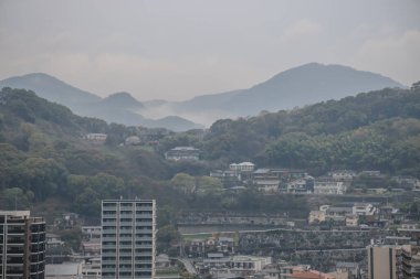 Modern binalar ve çevreleyen yeşil tepeler,