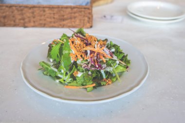 Yapraklı taze salata, doğranmış havuç ve sos.