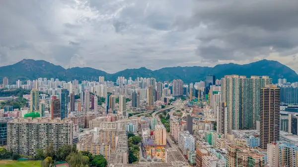 Dramatik bulutlu gökyüzünün altında manzaralı dağlarla çevrili binalar..