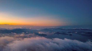Parlak bir günbatımının altında bulutlu bir şehrin ufuk çizgisini gösteren nefes kesici manzara.