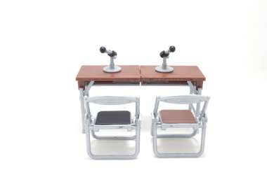 Mikrofon ve sandalyelerle donatılmış iki masanın resmi