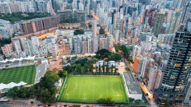 Şehir mimarisi, alacakaranlıkta parlak bir futbol sahasını çevreledi.