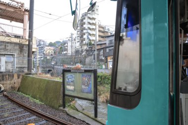 28 Mart 2025 Bir turkuaz şehir tramvayı küçük bir istasyonda duruyor.