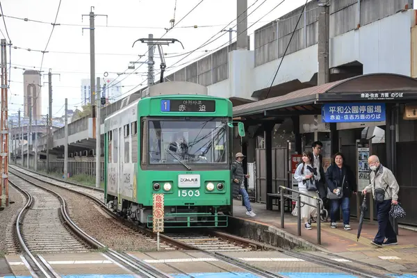 28 Mart 2025 yeşil tramvay bir şehir istasyonunda yolcuların binişi ve inişi olarak duruyor..