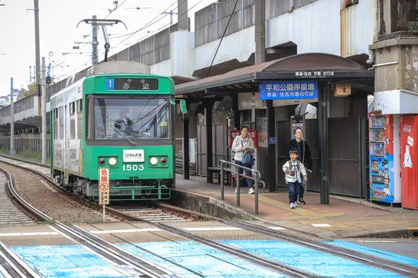 28 Mart 2025 yeşil tramvay bir şehir istasyonunda yolcuların binişi ve inişi olarak duruyor..