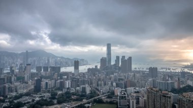 Bulutlu gökyüzü, yüksek gökdelenli modern bir şehir siluetinin üzerinde süzülüyor.