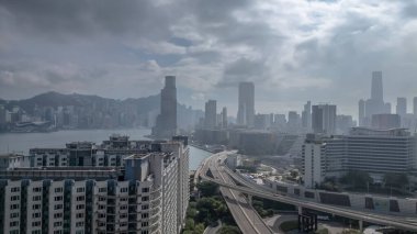 Etrafı yollarla çevrili yüksek bir konut binasının bulunduğu canlı şehir manzarası,