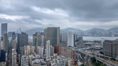 Etrafı yollarla çevrili yüksek bir konut binasının bulunduğu canlı şehir manzarası,