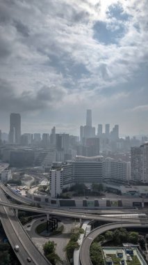 Etrafı yollarla çevrili yüksek bir konut binasının bulunduğu canlı şehir manzarası,