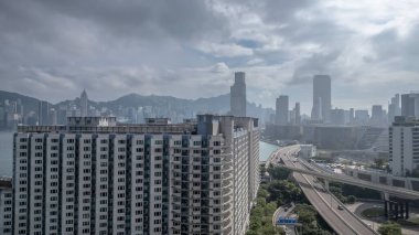 Etrafı yollarla çevrili yüksek bir konut binasının bulunduğu canlı şehir manzarası,