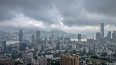 Bulutlu gökyüzü, yüksek gökdelenli modern bir şehir siluetinin üzerinde süzülüyor.