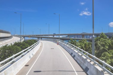 Temiz asfalt şeritli ve yeşil yapraklı yüksek bir yol.