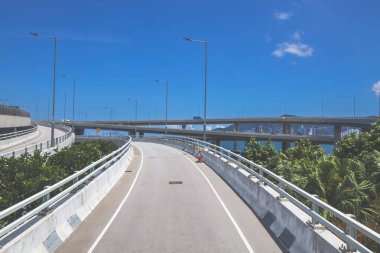 Temiz asfalt şeritli ve yeşil yapraklı yüksek bir yol.