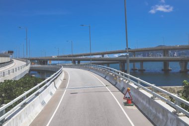 Temiz asfalt şeritli ve yeşil yapraklı yüksek bir yol.