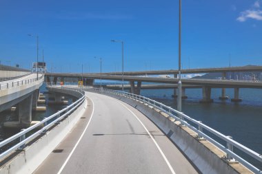 Temiz asfalt şeritli ve yeşil yapraklı yüksek bir yol.