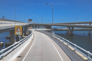 Temiz asfalt şeritli ve yeşil yapraklı yüksek bir yol.