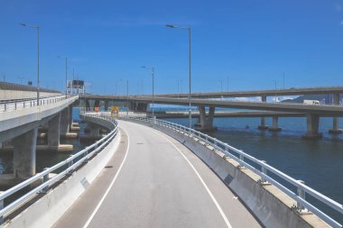 Temiz asfalt şeritli ve yeşil yapraklı yüksek bir yol.