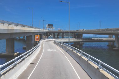 Temiz asfalt şeritli ve yeşil yapraklı yüksek bir yol.
