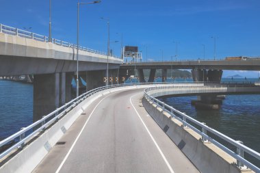 Temiz asfalt şeritli ve yeşil yapraklı yüksek bir yol.