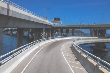 Temiz asfalt şeritli ve yeşil yapraklı yüksek bir yol.