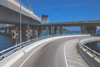 Temiz asfalt şeritli ve yeşil yapraklı yüksek bir yol.