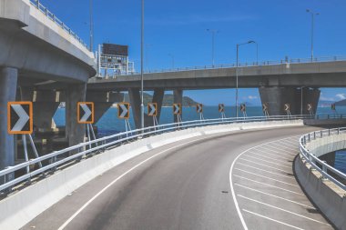 Temiz asfalt şeritli ve yeşil yapraklı yüksek bir yol.