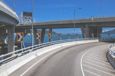Temiz asfalt şeritli ve yeşil yapraklı yüksek bir yol.