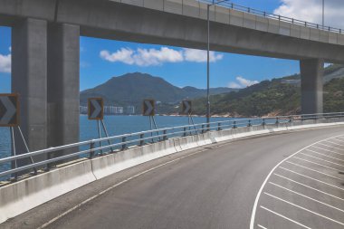 Temiz asfalt şeritli ve yeşil yapraklı yüksek bir yol.