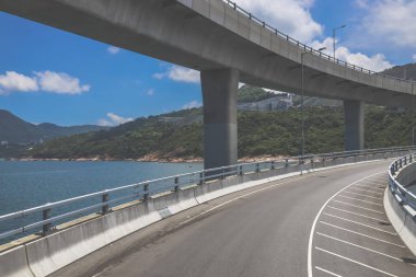 Temiz asfalt şeritli ve yeşil yapraklı yüksek bir yol.