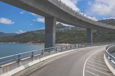 Temiz asfalt şeritli ve yeşil yapraklı yüksek bir yol.