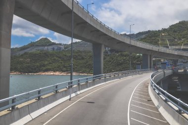 Temiz asfalt şeritli ve yeşil yapraklı yüksek bir yol.