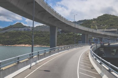 Temiz asfalt şeritli ve yeşil yapraklı yüksek bir yol.