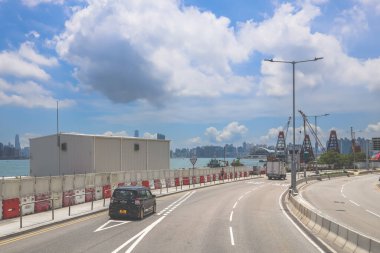 Kavisli bir karayolu, araçlar ve manzaralı bir şehir silueti içeren şehir yolu.