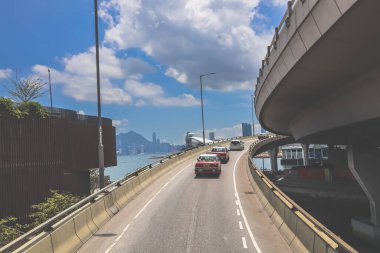 Kavisli bir karayolu, araçlar ve manzaralı bir şehir silueti içeren şehir yolu.