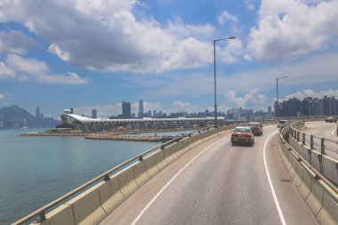 Kavisli bir karayolu, araçlar ve manzaralı bir şehir silueti içeren şehir yolu.